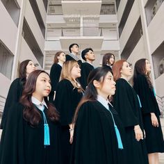 a group of young women standing next to each other in front of a building with their graduation gowns on