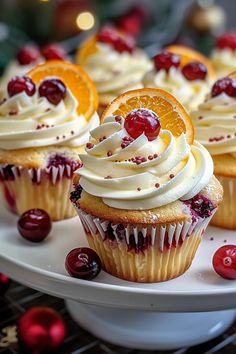 cupcakes with white frosting, orange slices and cranberries on a plate