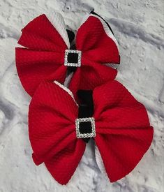 three red bows with white and black trims on them sitting in the middle of snow