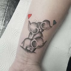 an elephant tattoo on the wrist with a heart in it's trunk and two elephants hugging each other