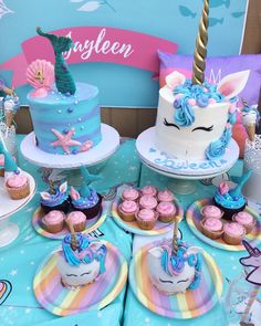 a table topped with cakes and cupcakes covered in blue frosted icing