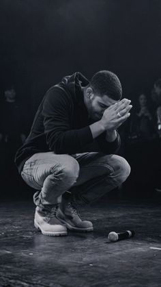 a black and white photo of a man kneeling on the ground with his hands together