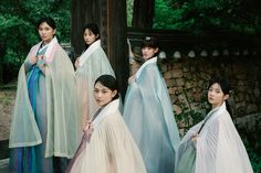 four women dressed in traditional japanese clothing standing next to each other and looking at the camera