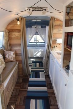 the interior of a tiny home with wood paneling and striped rugs on the floor