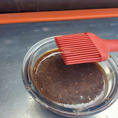 a red brush on top of a bowl filled with dirt