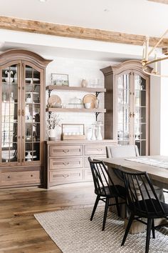 the dining room table is surrounded by black chairs and wooden hutch with glass doors