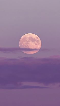 the full moon is seen through clouds in this purple and pink sky photo taken from an airplane