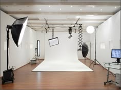 an empty studio with lighting equipment and lights on the floor in front of a white backdrop