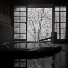 a large hot tub sitting inside of a bathroom next to a window with trees outside