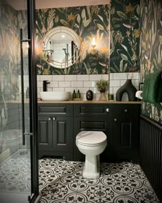 a bathroom with green and white wallpaper, black cabinetry, toilet and sink