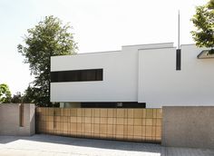 a white building sitting on the side of a road next to a tall wooden fence