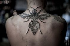 the back of a man's neck with a tattoo of a bee on it