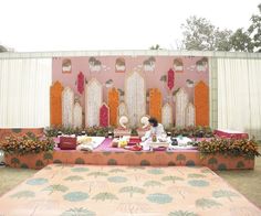 a person sitting at a table in front of a stage with flowers and decorations on it