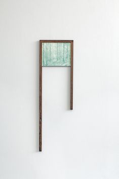 a piece of wood hanging on the wall next to a white wall with a green painting