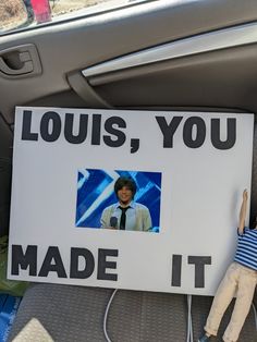 a sign that says louis, you made it with a doll in the back seat