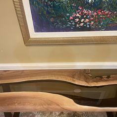 a piece of wood sitting on top of a wooden table next to a framed painting