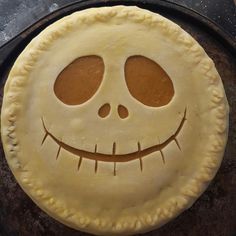 a pumpkin pie with an evil face on it's crust, ready to be baked