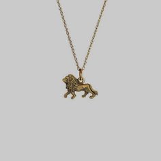 a gold necklace with a lion charm hanging from it's side on a chain