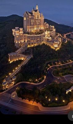 the hotel is lit up at night on top of a hill