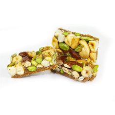 two pieces of granola bar with nuts and pistachios on top, cut in half