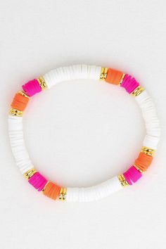 an orange and white beaded bracelet with gold clasps on a white table top