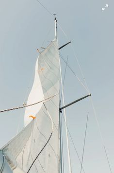 a sailboat with white sails and masts against a blue sky