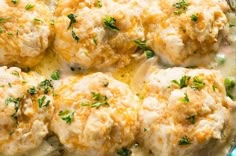 a casserole dish with meatballs covered in cheese and parsley on top