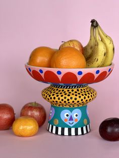 a bowl filled with fruit sitting on top of a table next to apples and oranges