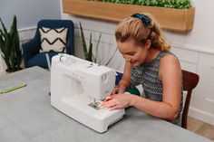 a woman sitting at a table using a sewing machine to sew something on it