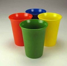 four different colored cups sitting next to each other on a white surface with no one around them