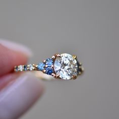 a person holding a diamond and blue sapphire ring