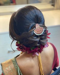 the back of a woman's head with flowers in her hair and an elaborate brooch