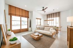 a living room filled with lots of furniture next to tall windows and wooden shutters