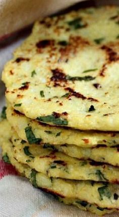 there is a stack of flat breads on the table with green leaves in it