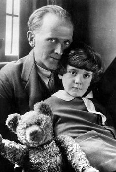 an old black and white photo of a man holding a child with a teddy bear