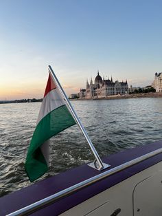 an italian flag is waving on the back of a boat in front of a castle