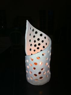 a lit candle holder sitting on top of a black table with polka dot paper in it