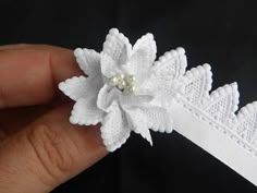 a hand holding a white flower on top of a headband