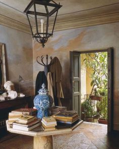 a table topped with lots of books next to a lamp hanging from a ceiling fixture