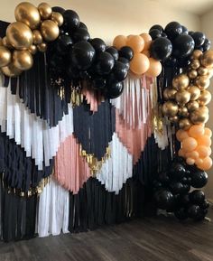 black, gold and white balloons are hanging on the wall in front of a backdrop