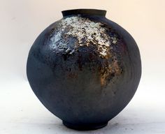 a black vase with white speckles on the top and bottom, sitting against a white background