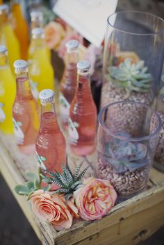 there are many bottles on the table with flowers and plants in them, including roses