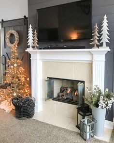 a living room decorated for christmas with a fireplace and tv above the fire place, surrounded by holiday decorations