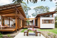 an outdoor area with tables, chairs and a house in the background that is surrounded by trees