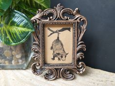 an ornate frame with a picture of a porcupine on it next to a potted plant