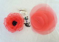 an orange flower sitting on top of a white table next to some beads and a pair of scissors