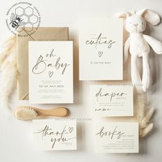 the wedding stationery is laid out on top of each other, with a teddy bear next to it