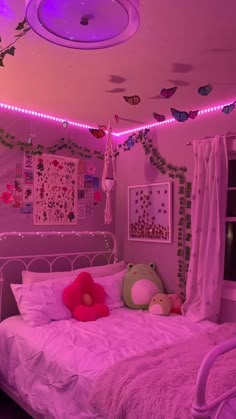 a bedroom decorated in pink and white with fairy lights on the ceiling above the bed