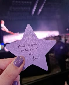 a person holding up a purple star with writing on it