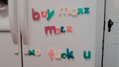 colorful magnets on the side of a refrigerator saying buy more milk, no tuk u